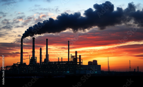 Industrial landscape with a factory emitting smoke from chimneys at sunset, highlighting air pollution and environmental impact.