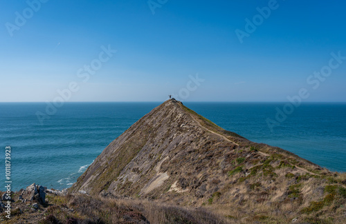 Hiker standing at the clifftop at the Higher Sharpnose Point on the South West Coast Path and enjoying the amazing view photo