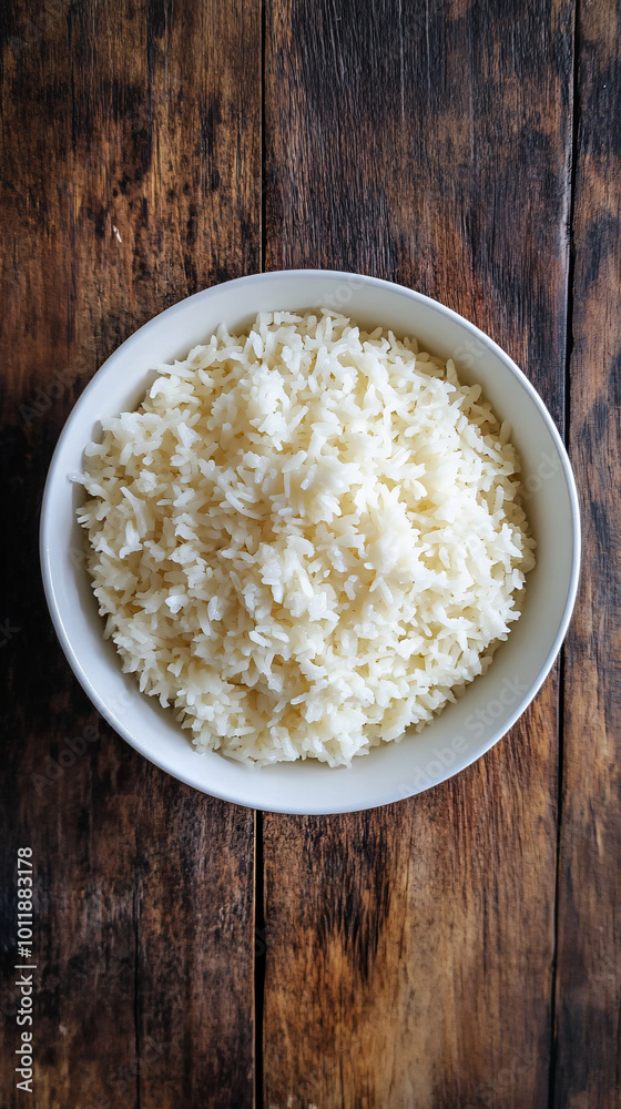 Overflowing white bowl filled with a generous serving of cooked white rice on a dark wooden table Overflowing white bowl filled with a generous serving of cooked white rice on a dark wooden table