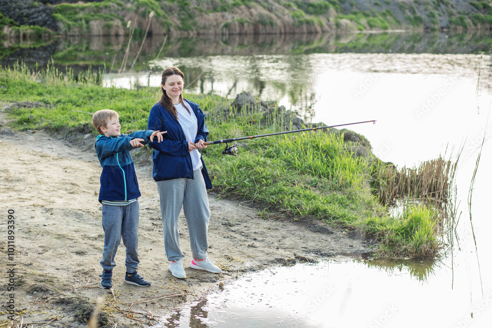 Mother and son fishing and pointing by lake. Family time. Mother and son fishing and pointing by lake. Family time.