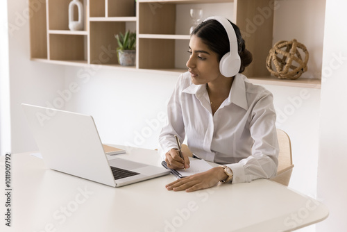 Wallpaper Mural Young Indian woman engaged in e-learning take part in business conference online watch video class write notes get knowledge remotely. Expert consultant in headset assist client on distance via pc app Torontodigital.ca