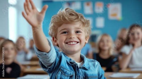 A cheerful young boy in a denim jacket enthusiastically raises his hand in a lively classroom setting, eager to participate and engage with learning activities. photo