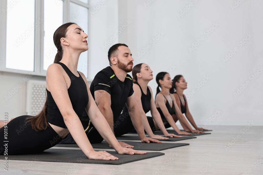 Obraz premium Group of people practicing yoga on mats in class. Space for text