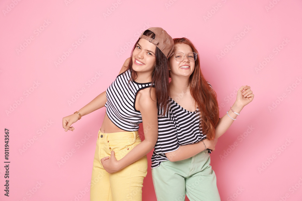 Happy teenage girls posing on pink background