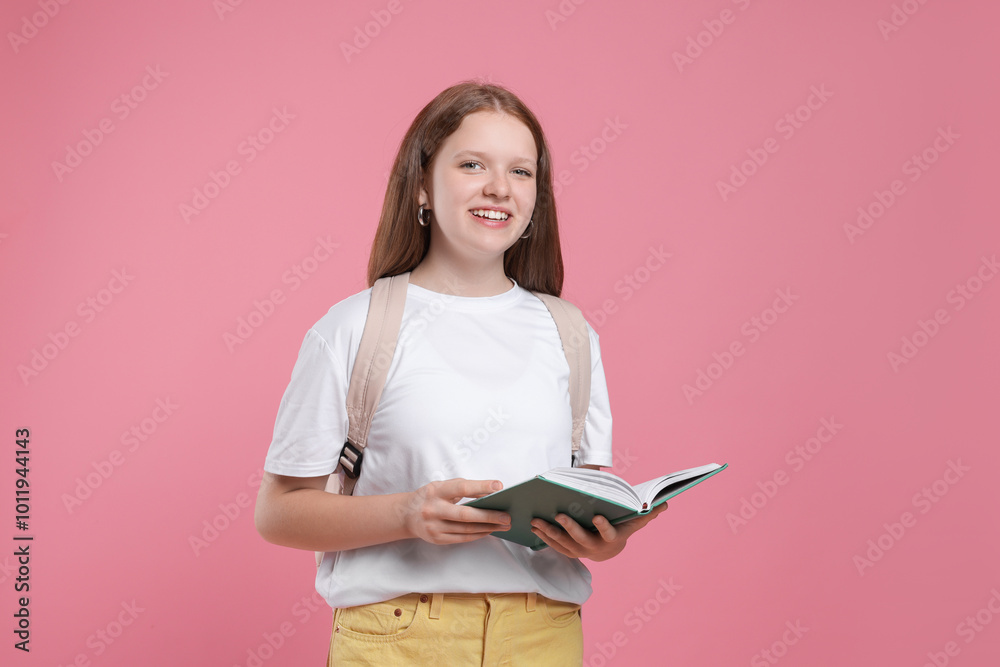 Teenage girl with backpack and open book on pink background Teenage girl with backpack and open book on pink background