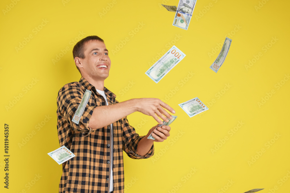 Happy man throwing money on yellow background, space for text Happy man throwing money on yellow background, space for text