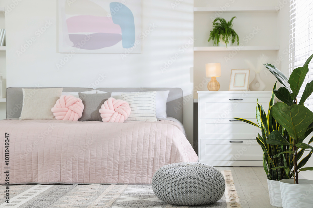 Naklejka premium Large bed, houseplants and decorative elements in room. Stylish bedroom interior