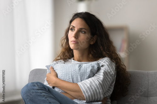 Billede på lærred Serious pensive pretty Latin woman sitting on sofa at home, looking away in deep