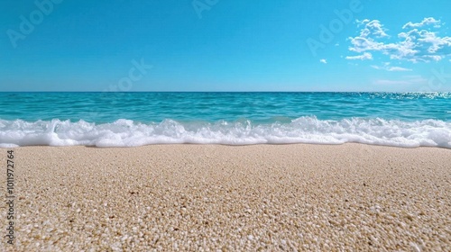 A photostock images of a sandy beach with waves gently crashing onto the shore