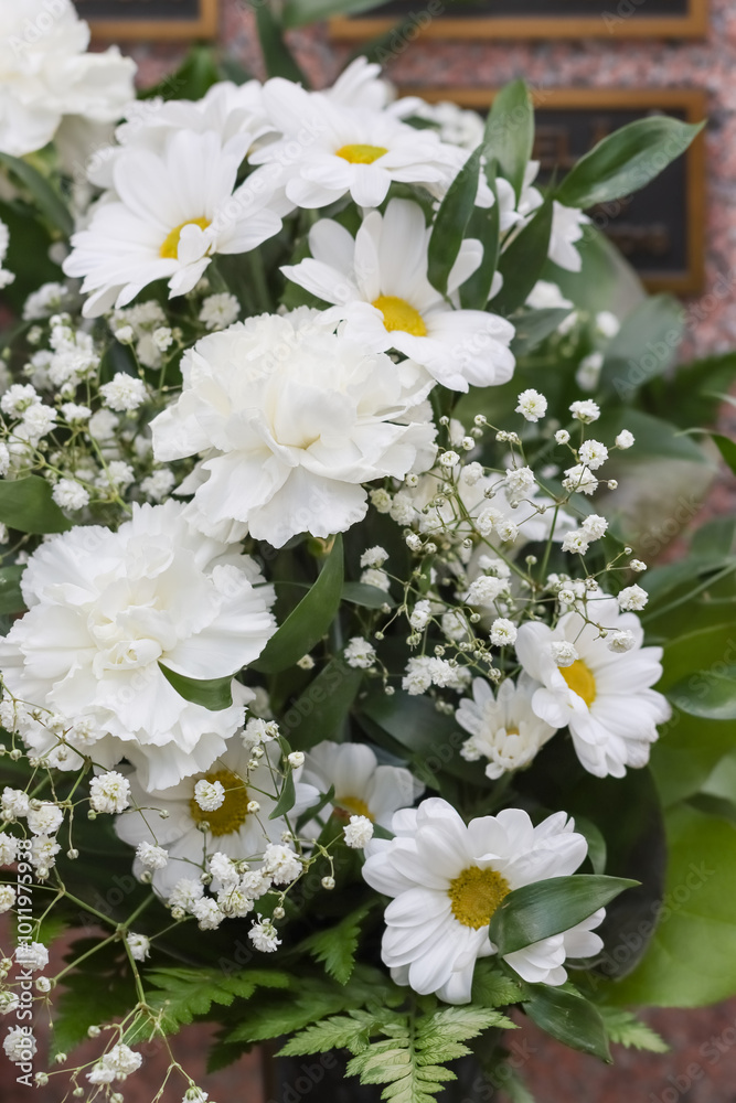 Flower arrangement. Beautiful white grave flowers in the cemetery. Relatives want to remember the deceased with flowers. A beautiful bouquet comforts grieving relatives. Flower arrangement. Beautiful white grave flowers in the cemetery. Relatives want to remember the deceased with flowers. A beautiful bouquet comforts grieving relatives.