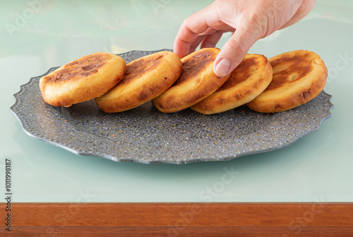 Hand taking a delicious boyacense arepa from an elegant grey plate. Traditional Colombian gastronomy. photo