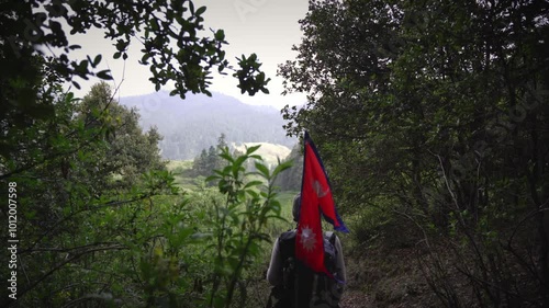 A Man waking in the Jungle of Khaptad National Park with flag of Nepal, travelling in Farwest Nepal photo