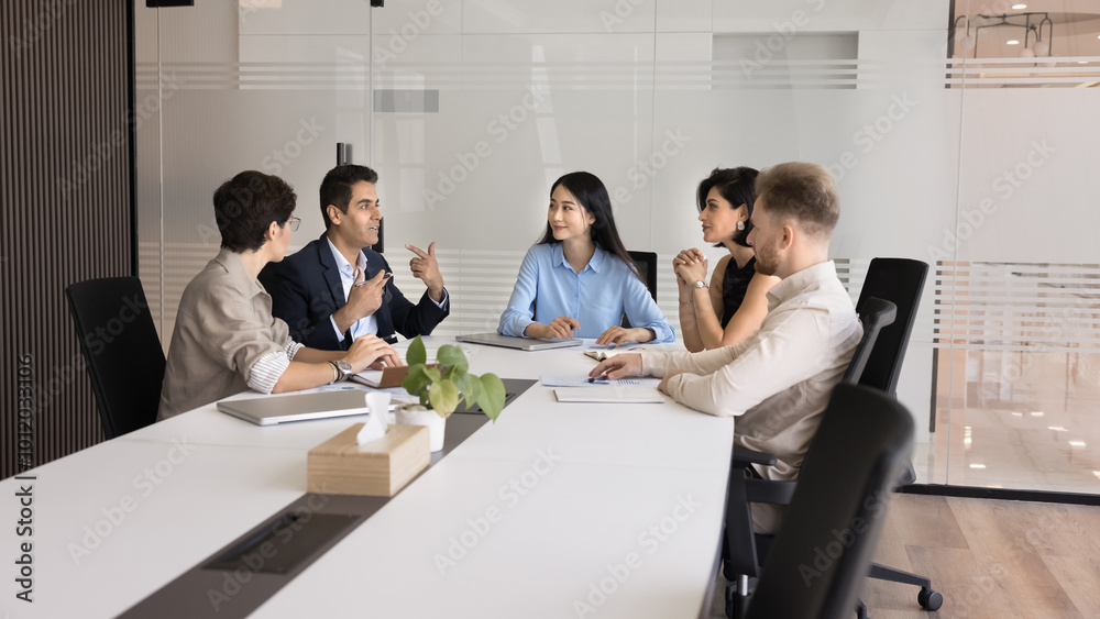 Fototapeta premium Multiethnic business team meeting at large table for teamwork, offline communication, brainstorming on project strategy. Diverse group of colleagues talking in office workspace interior