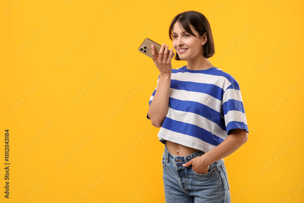 Beautiful woman recording voice message via smartphone on yellow background, space for text Beautiful woman recording voice message via smartphone on yellow background, space for text