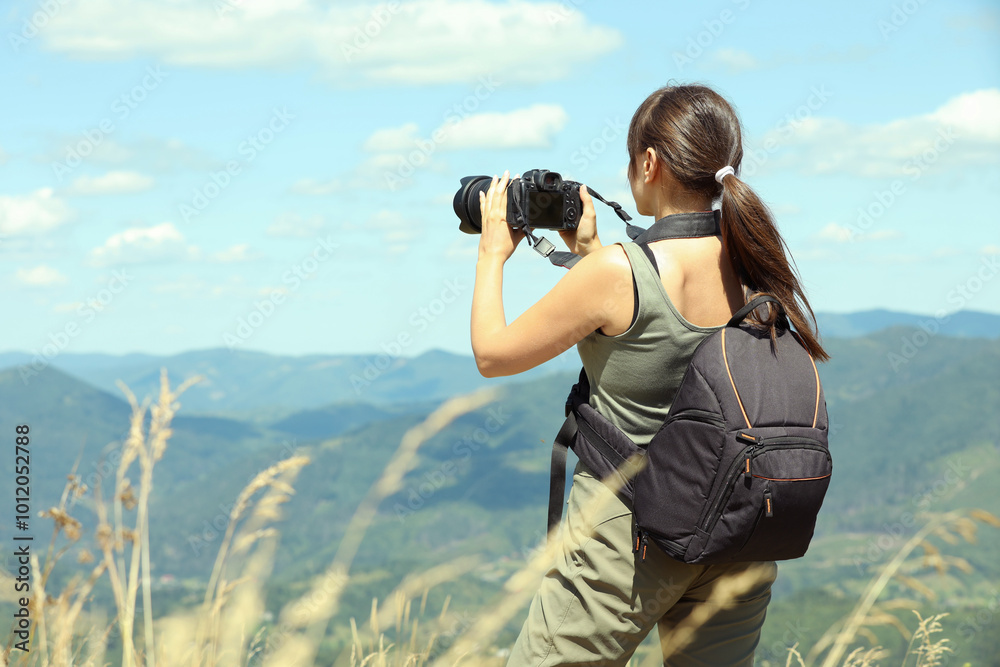 Photographer with backpack and camera taking picture of beautiful mountains, back view Photographer with backpack and camera taking picture of beautiful mountains, back view