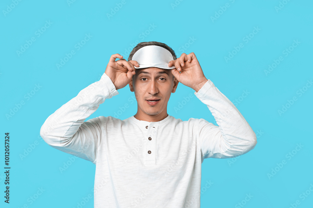 Overslept man with sleep mask on light blue background Overslept man with sleep mask on light blue background
