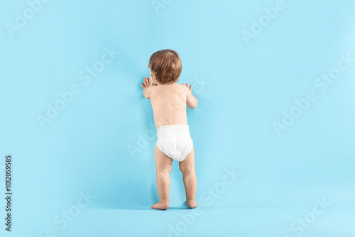 Foto Little child in diaper on light blue background, back view