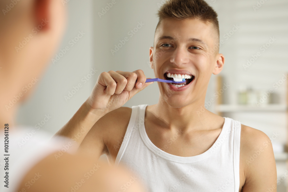 Young man brushing his teeth in bathroom Young man brushing his teeth in bathroom