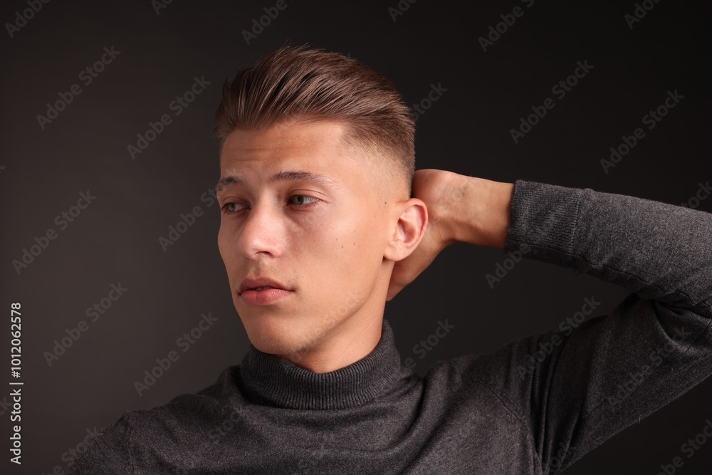 Obraz premium Confident young man with stylish haircut on black background