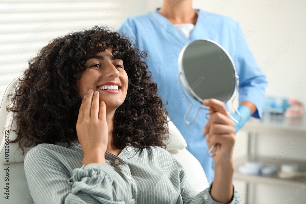 Patient looking in mirror and doctor in clinic, selective focus. Dental veneers Patient looking in mirror and doctor in clinic, selective focus. Dental veneers