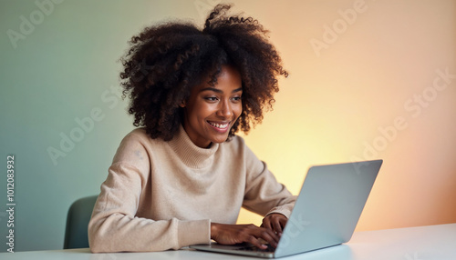 A young Black woman with curly dark hair working on a laptop at a desk