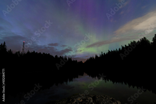 Aurora Borealis, Norhtern Lights above the trees in the Norwegian forest around the Trondheim, KP4 or KP5 solar storm, above the lake, reflection of aurora photo