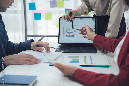 Business Analysis: A team of professionals huddle around a laptop, engaged in a critical analysis of data charts and graphs.