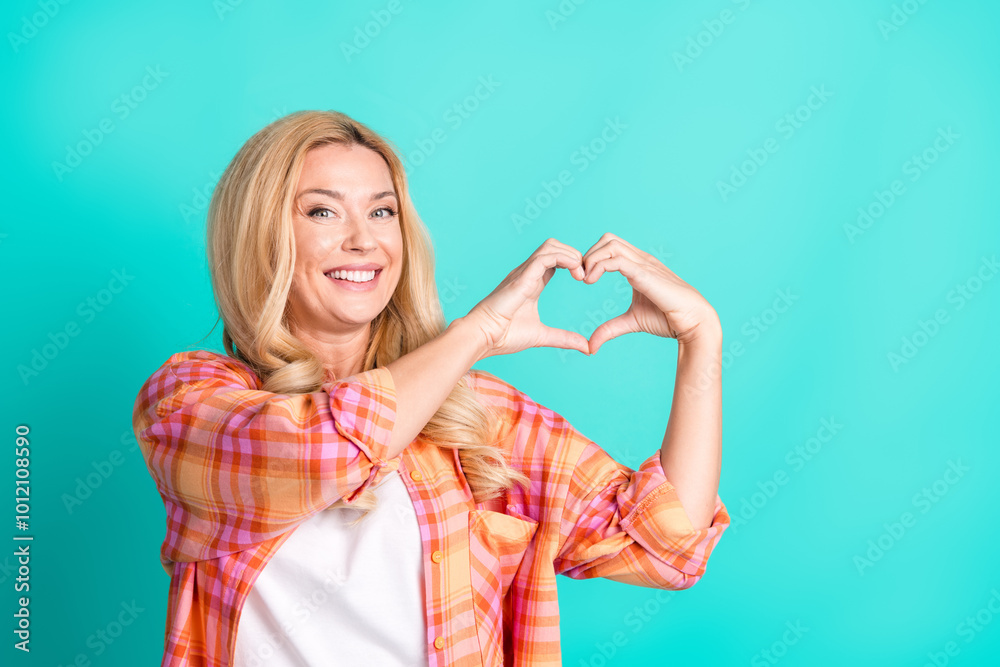 Photo portrait of lovely mature lady show heart symbol dressed stylish plaid garment isolated on cyan color background Photo portrait of lovely mature lady show heart symbol dressed stylish plaid garment isolated on cyan color background