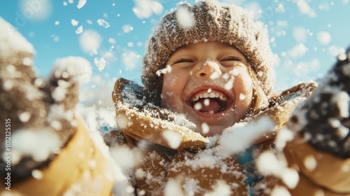 A cheerful child, bundled in winter clothes, is laughing while playing in the snow on a sunny day, capturing pure joy and unbridled winter fun. photo