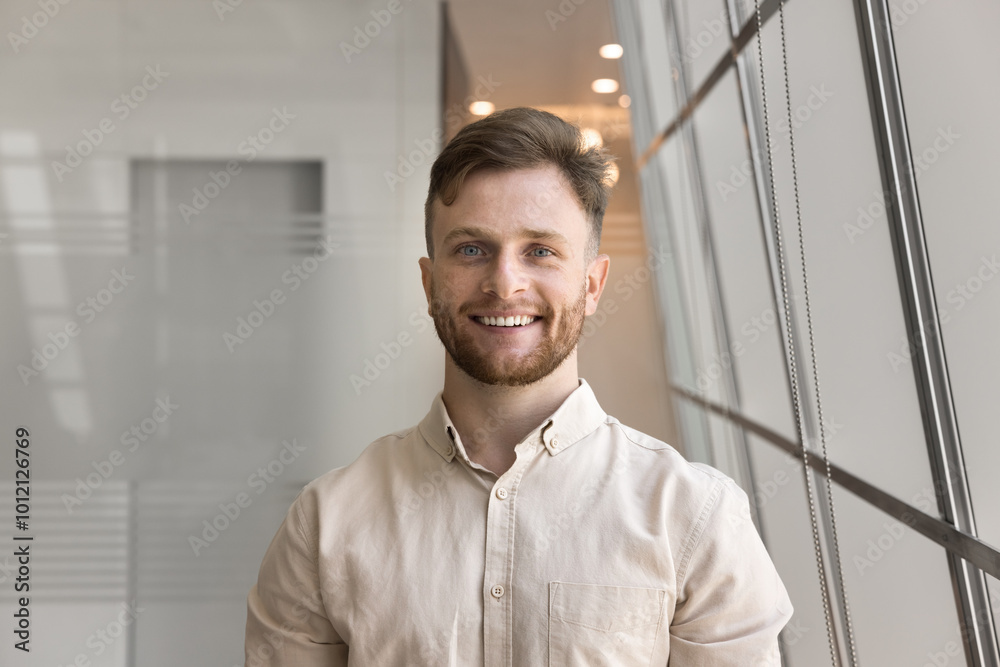 Happy young Caucasian businessman posing for portrait, looking at camera, smiling, posing in office business center space. Handsome entrepreneur, professional, manager screen view head shot Happy young Caucasian businessman posing for portrait, looking at camera, smiling, posing in office business center space. Handsome entrepreneur, professional, manager screen view head shot