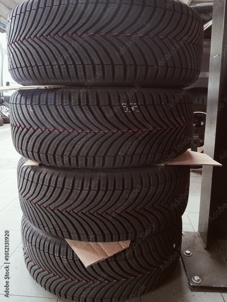 Old car tires stacked in a row at a tire shop, closeup of photo