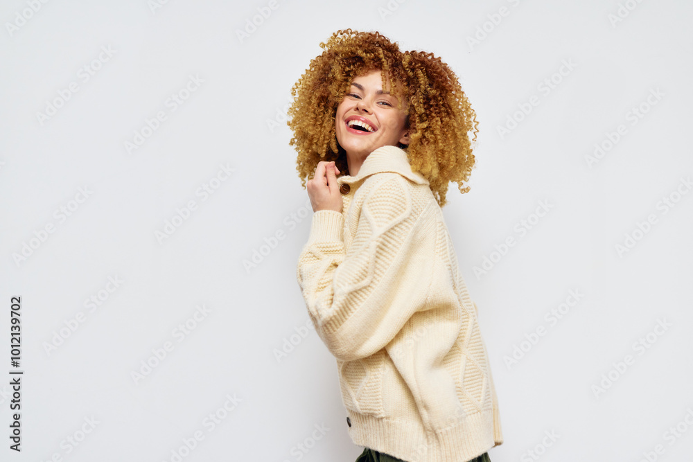Smiling young woman with curly hair wearing a cozy sweater against a light background Joyful expression conveying happiness and confidence, ideal for lifestyle imagery Smiling young woman with curly hair wearing a cozy sweater against a light background Joyful expression conveying happiness and confidence, ideal for lifestyle imagery