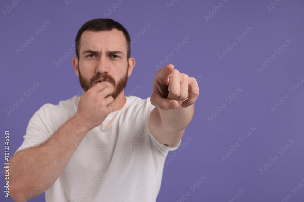 Young man blowing whistle on purple background, space for text Young man blowing whistle on purple background, space for text