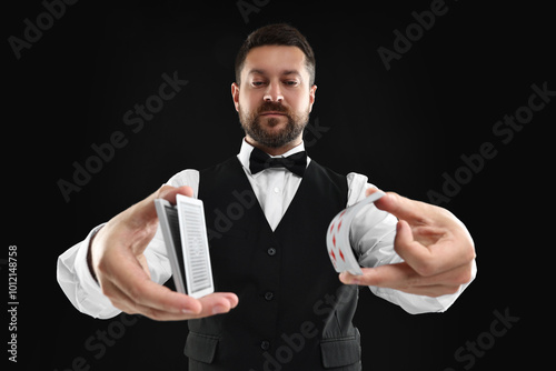 Professional croupier shuffling cards on black background photo