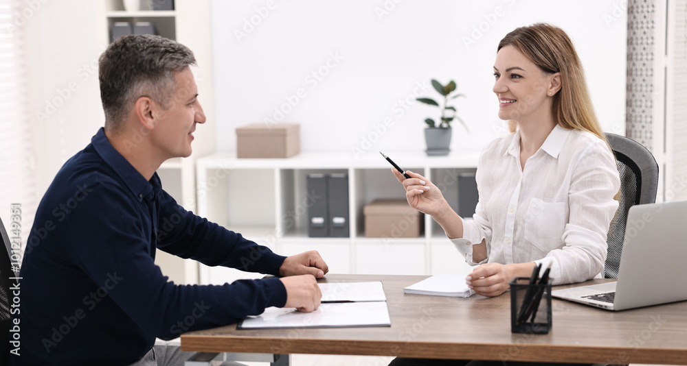 Banker working with client at wooden table in office Banker working with client at wooden table in office