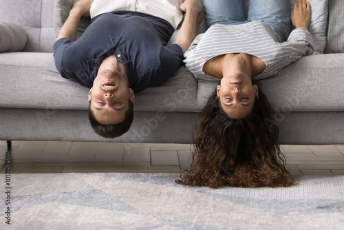 Εκτύπωση καμβά Sleeping young married couple lying upside down on home sofa, having fun, keepin