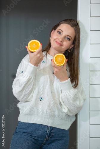Healthy food concept. A young beautiful girl holds orange halves in her hands
