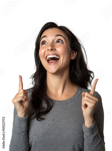 Joyful young woman with long dark hair pointing up against a plain backdrop