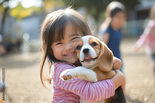 A cheerful preschooler with Japanese heritage, tightly hugging a fluffy beagle puppy on a playground. The joy on her face, with friends playing nearby, captures the essence of childhood happiness. photo