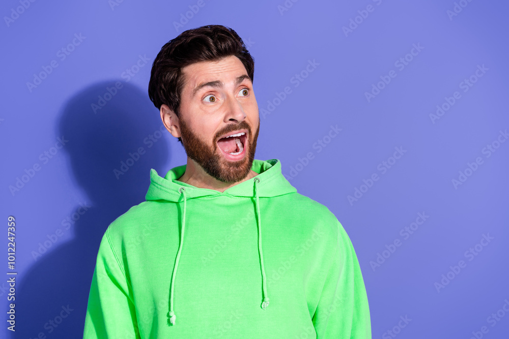 Photo portrait of handsome mature age surprised reaction man wearing bright green hoodie sportswear isolated on violet color background Photo portrait of handsome mature age surprised reaction man wearing bright green hoodie sportswear isolated on violet color background