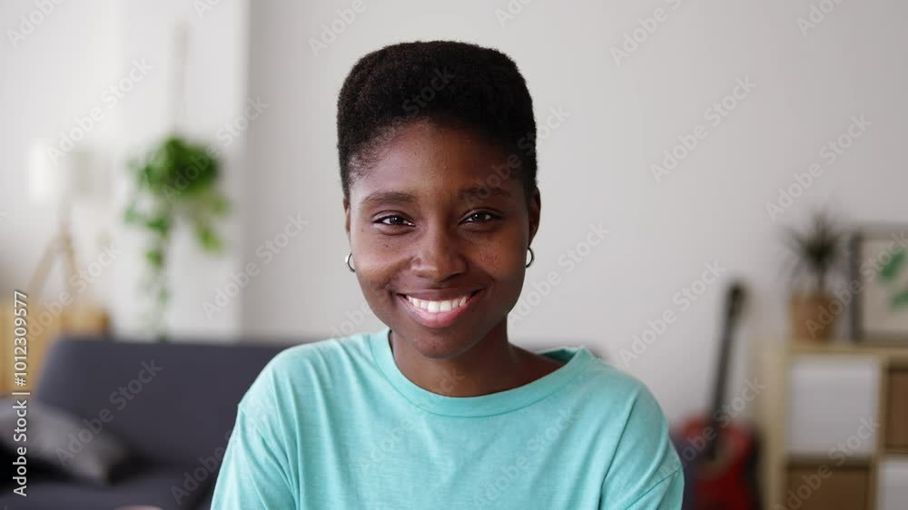 Young happy black woman smiling at camera standing in the living room at home. Positive African people concept. Young happy black woman smiling at camera standing in the living room at home. Positive African people concept.