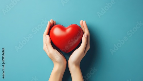 hands hold a red heart on a blue background.