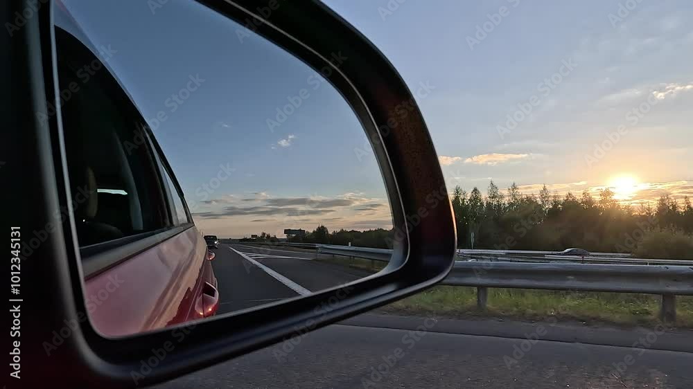 Video shooting in motion, view in the rear view side mirror of a auto, driving a red car along the road