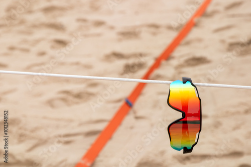 Óculos de sol pendurado em corda de quadra de vôlei de praia photo