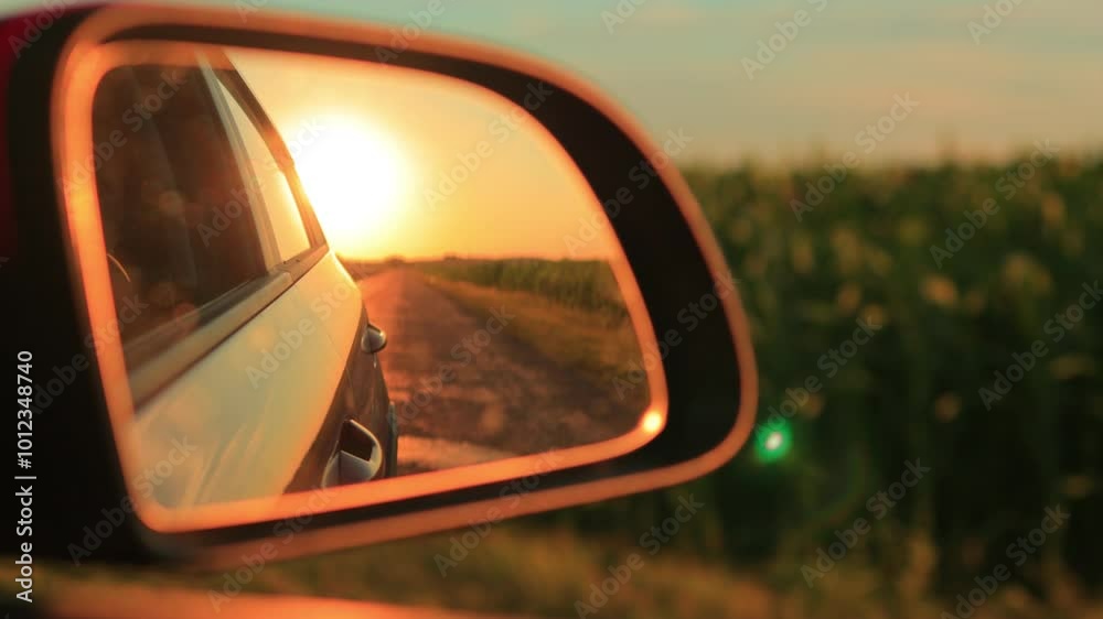 The sun is reflected in the mirror and window, evening road. View in the side rear view mirror of a car driving along the highway, in a red car The sun is reflected in the mirror and window, evening road. View in the side rear view mirror of a car driving along the highway, in a red car