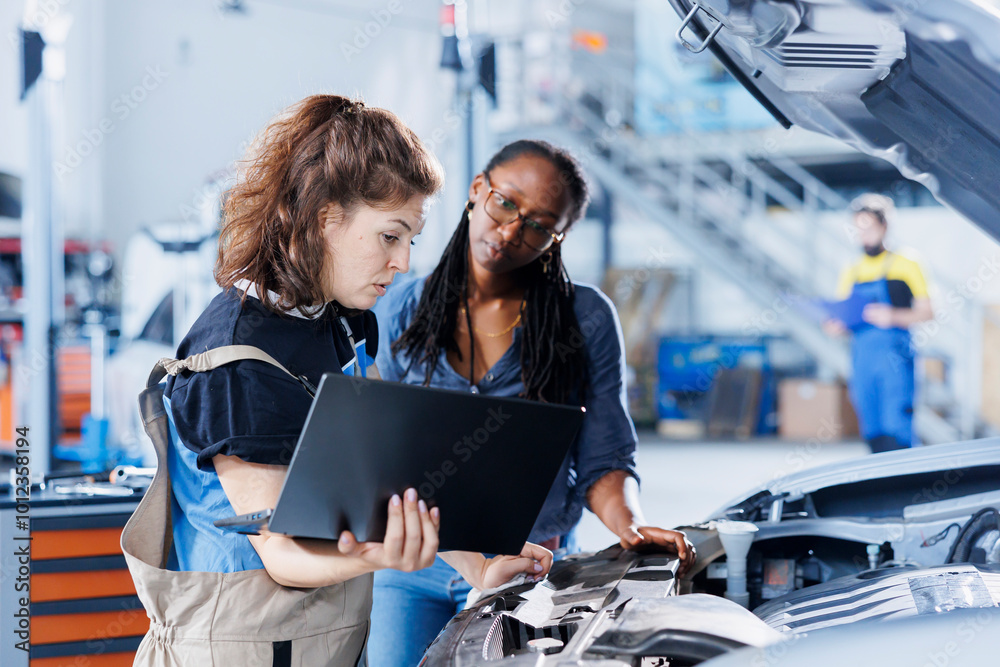 © DC Studio - Mechanic in car service ordering new engine for damaged vehicle using laptop. Employee next to client looking online for components to replace old ones in malfunctioning automobile