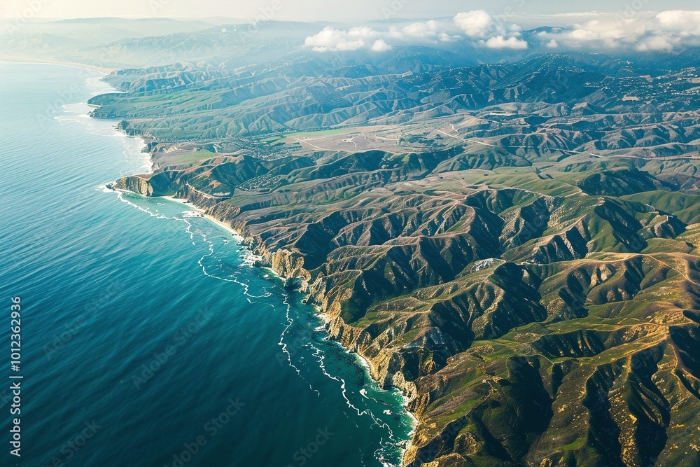 Fototapeta premium Aerial view of rugged coastline with turquoise waters and green mountains
