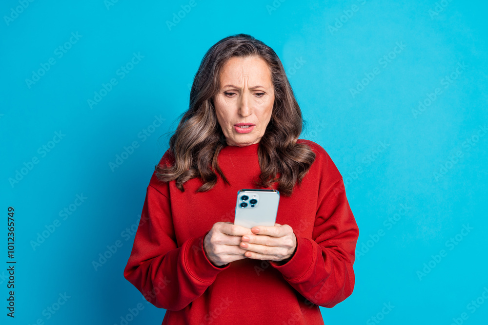 Portrait of nice aged woman use phone chatting wear red sweater isolated on blue color background Portrait of nice aged woman use phone chatting wear red sweater isolated on blue color background