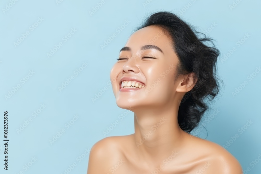 Portrait of a beautiful young asian woman laughing over blue background Portrait of a beautiful young asian woman laughing over blue background