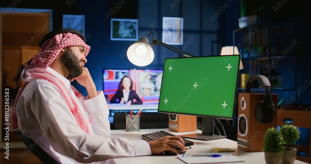 Arabic man looking at chroma key computer screen while working from ...